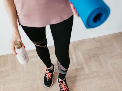 Close-up of a yoga mat and a water bottle on a wooden floor.